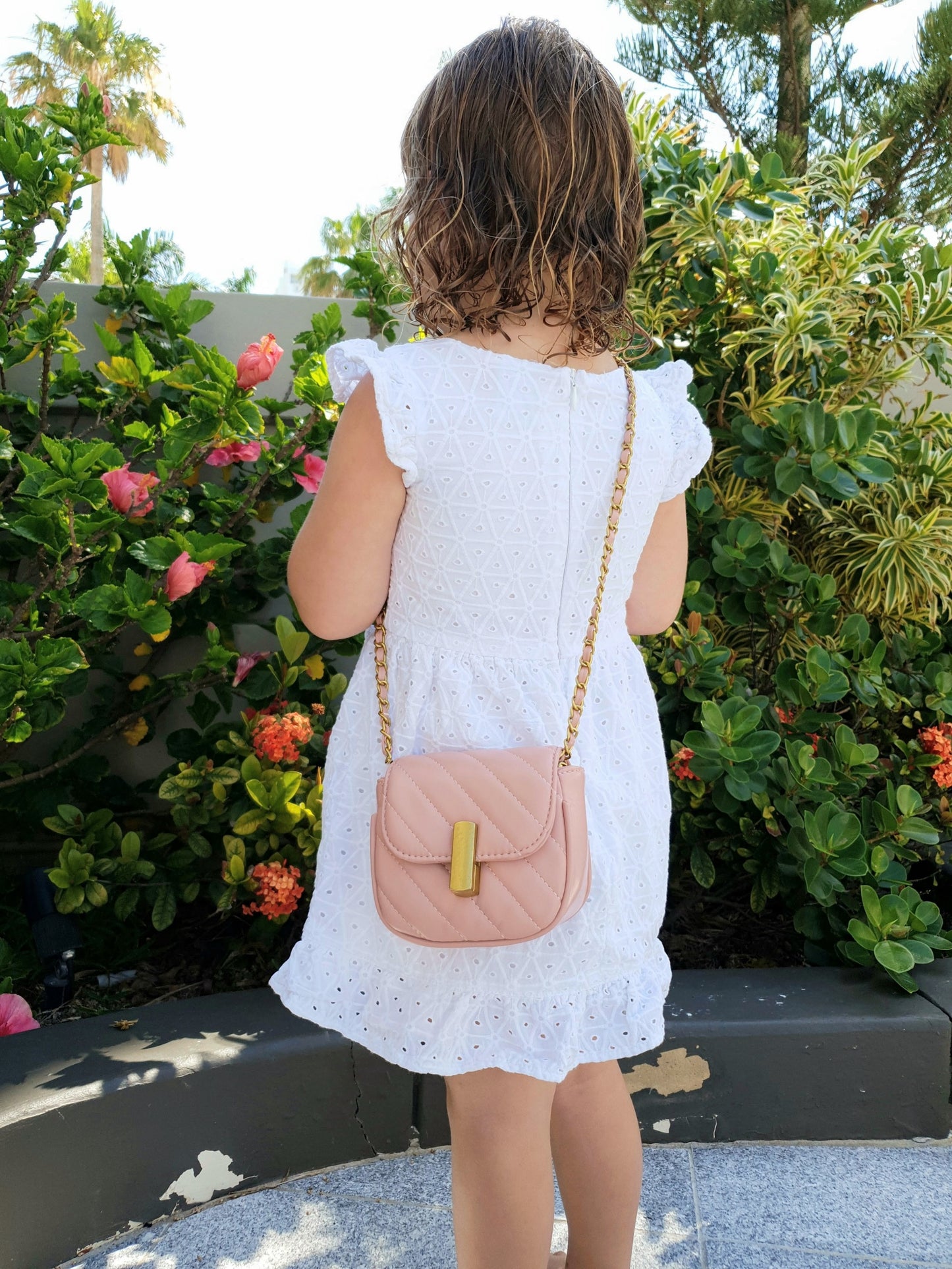 Girl wearing child bag - pink in colour with gold shoulder straps. Mother Daughter bag 